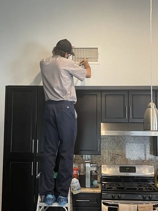 Technician inspecting an air vent during HVAC service in Merrydale